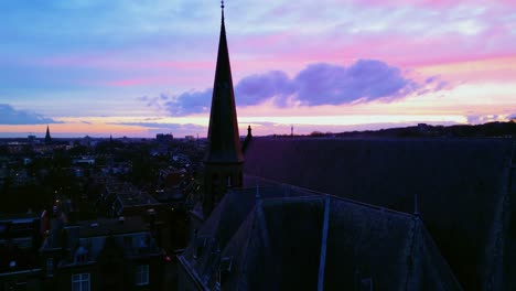Crane-up-revealing-Arnhem-city-centre-behind-church-in-pink-sunset-light-aerial