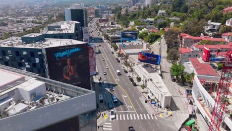 Drone-Flying-Over-Sunset-Boulevard-in-Daytime,-Bright-Sunny-Day-in-West-Hollywood-Following-Vehicle-Driving-on-Street-Below