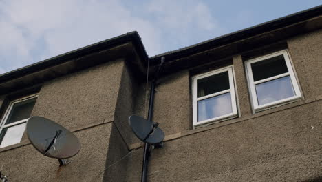 Haus-Mit-Zwei-Fenstern-Und-TV-Antennen,-Niedriger-Winkel-Mit-Blauem-Himmel-Dahinter