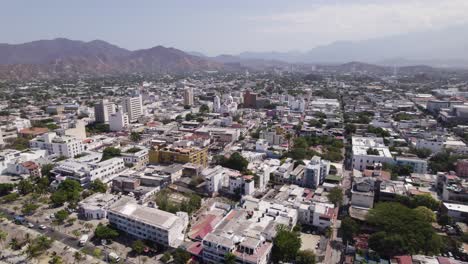 Cityscape-of-modern-tropical-city-Santa-Marta,-Colombia,-mountains-in-background,-aerial-view