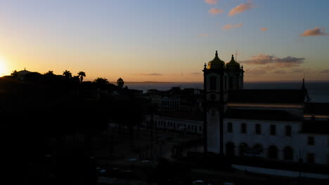Luftaufnahme-Der-Rückseite-Der-Kirche-Nosso-Senhor-Do-Bonfim,-Der-Nachbarschaft-Und-Dem-Meer-Im-Hintergrund,-Bei-Sonnenuntergang,-Salvador,-Bahia,-Brasilien