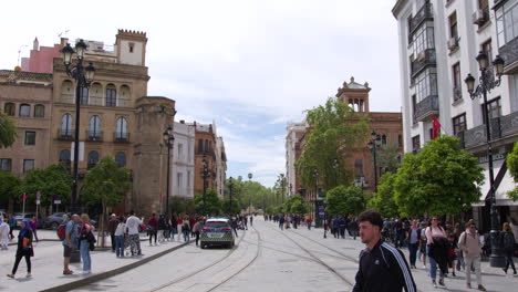 Timelapse-Del-Tranvía-Metrocentro-Cruzando-El-Centro-De-Sevilla,-Calles-Concurridas-De-Andalucía-Con-Peatones-Cruzando-La-Calle