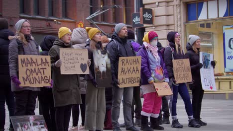 Protestors-stand-still,-quiet-on-city-street,-placards-oppose-cruelty