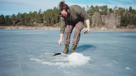 Man-Pulling-The-Fishing-Rod-Line-With-Catch-Fish-On-Frozen-Lake