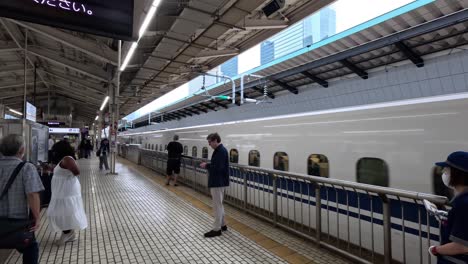 El-Shinkansen-Serie-N700-Llega-A-La-Estación-De-Tokio,-Mientras-Visitantes-Y-Viajeros-Se-Preparan-Para-Abordar,-Encarnando-La-Esencia-De-Los-Viajes-Y-Los-Desplazamientos-En-Tren.