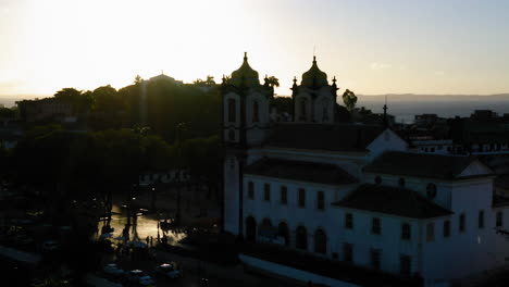 Aerial-view-of-Nosso-Senhor-do-Bonfim-church-back-side,-the-neighbourhood-and-the-ocean-at-background,-at-sunset,-Salvador,-Bahia,-Brazil