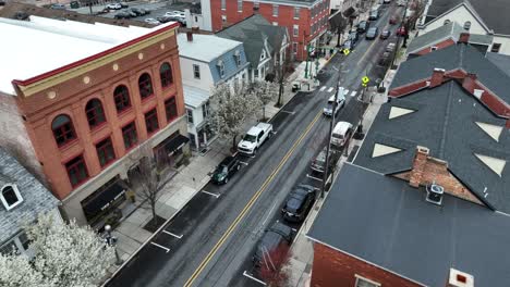 Aerial-birds-eye-flight-over-main-street-of-american-town-with-blooming-trees