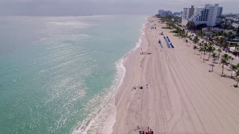 Impresionante-Vista-Aérea-De-La-Costa-De-La-Playa-Con-Edificios-En-El-Costado-Agua-Azul-Cielo-Azul-Palmeras-Ft