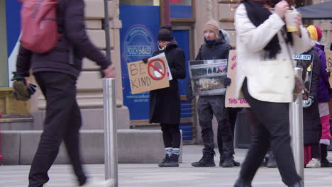 City-pedestrians-walk-past-people-protesting-animal-cruelty-on-street