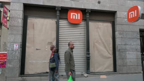 Los-Peatones-Pasan-Por-Una-Multinacional-China-Cerrada-De-Tecnología-Y-Electrónica,-La-Tienda-Insignia-De-Xiaomi-En-Madrid,-España