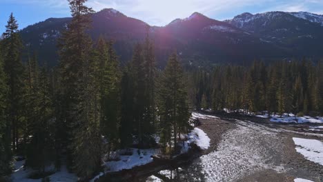 Beautiful-view-of-sun-peaking-through-mountains-with-river-and-evergreen-forest-in-Cle-Elum-during-dusk-in-Washington-State