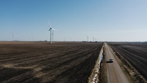 Drone-shot-of-a-maintenance-truck-driving-away-from-wind-turbines