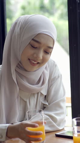 An-upwardly-mobile-Asian-Muslim-woman-enjoying-a-relaxing-moment-in-the-coffee-shop-on-a-bright-sunny-day