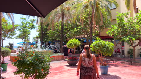 Caminando-Detrás-De-Una-Chica-Vestida-De-Verano-En-El-Casco-Antiguo-De-Estepona,-Día-Soleado-En-Andalucía-España,-Destino-De-Vacaciones,-Toma-De-4k