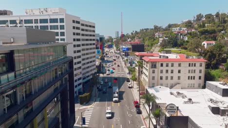 Aerial-Drone-Footage-of-Sunset-Boulevard-in-Daytime,-Cars-Below-and-Large-Billboard-Advertisements-Lining-Iconic-Street
