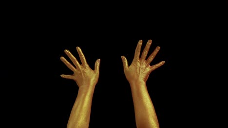 Hands-adorned-with-shimmering-gold-paint-against-a-dark-backdrop,-embodying-the-art-of-expression-through-various-gestures-like-clapping,-stretching,-and-uplifting-movements