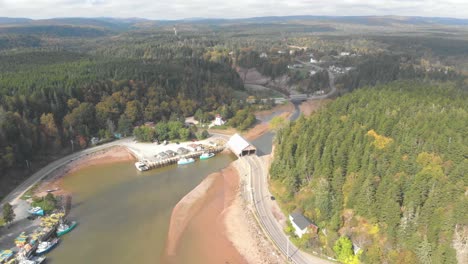 Aerial-shot-of-a-covered-bridge-with-cars-going-under-it-on-the-coast-of-St,-Martins,-New-Brunswick-on-a-sunny-day