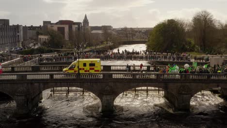 Luftaufnahme-Des-Corrib-Flusses-Mit-Einer-Seltsamen-Lachsbrücke-Im-Blick,-Während-Die-Leute-Die-Parade-Beobachten