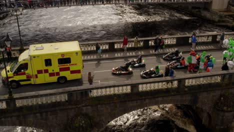 Characters-dressed-up-in-fun-whimsical-costumes-walk-and-sit-by-go-kart-racers-on-Salmon-Weird-Bridge