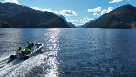 Vuelo-Bajo-Con-Drones-Adelantando-Al-Barco-Zodiac-Rozando-El-Fiordo-Veafjorden,-Noruega