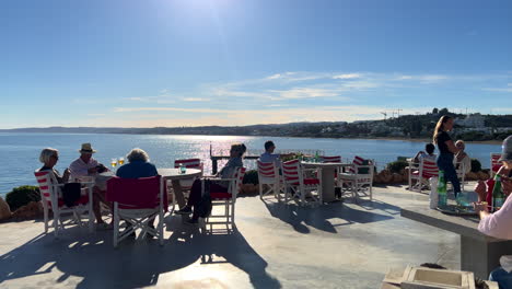 Gente-Sentada-En-Un-Restaurante-Con-Vistas-Al-Mar-En-La-Playa-De-Estepona,-Día-Soleado-En-Andalucía-España,-Destino-De-Vacaciones-De-Verano,-Toma-De-4k