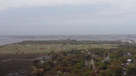 Wide-descending-aerial-shot-of-the-USS-Yorktown-aircraft-carrier-at-Patriot's-Point-from-Shem-Creek-on-a-hazy-day-in-Mount-Pleasant,-South-Carolina