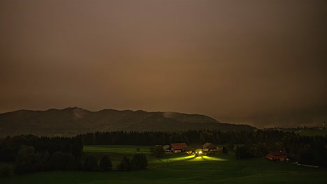 Panoramic-time-lapse-of-illuminated-rural-village-countryside-valley-time-lapse-between-dark-mountain-range-and-dusk-cloudy-skyline-in-motion