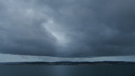 Schwere-Dunkle-Wolken-über-Der-Küstenstadt-Und-Dem-Wasser