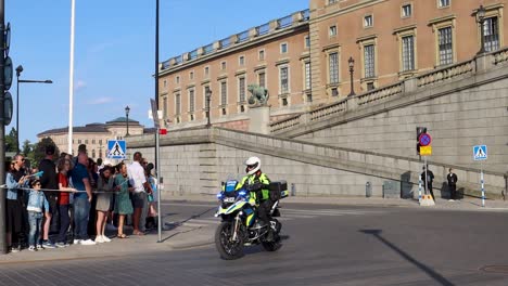 Police-officers-drive-motorcycles-by-Swedish-Royal-Palace,-slo-mo