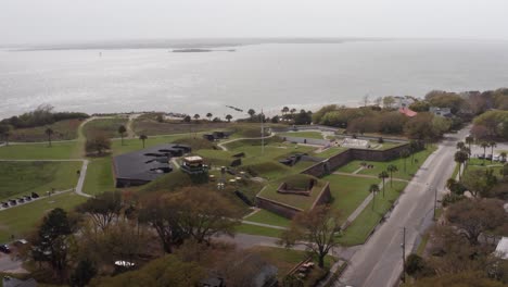 Descending-and-panning-aerial-shot-of-historic-Fort-Moultrie-along-the-Atlantic-Coast-during-a-day-with-low-visibility-on-Sullivan's-Island,-South-Carolina