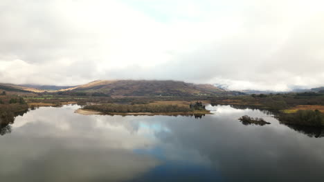 Upward-Linear-Drone-View-of-Majestic-Mountain-Lake-Surrounded-by-Peaks-with-Abandoned-Castle