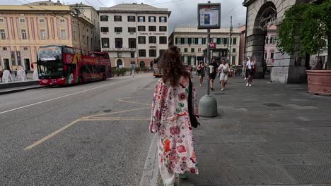 A-woman-wearing-patterned-loose-clothing-walking-along-pavement-in-town-square