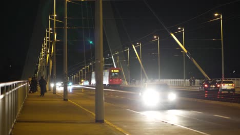 Un-Tren-Local,-Coches-Y-Gente-Pasando-Por-El-Severinsbrücke-En-Colonia,-Alemania,-De-Noche.