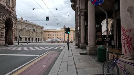 Clip-Portátil-Que-Muestra-La-Carretera-Y-El-Cruce-De-La-Ciudad,-Con-Gente-Caminando-Y-Edificios-Tradicionales-En-Italia