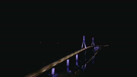 Night-aerial-shot-of-illuminated-Replot-Bridge-in-Finland,-car-driving-on
