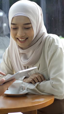 Una-Mujer-Musulmana-Asiática-Con-Movilidad-Ascendente-Que-Disfruta-De-Un-Momento-Relajante-En-La-Cafetería-En-Un-Día-Soleado