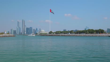 Pan-shot-og-Abu-Dhabi-skyline-and-UAE-flag-,-United-Arab-Emirates