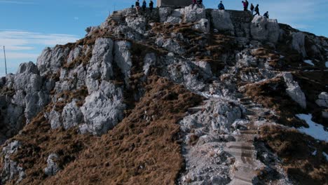 Aerial-rising-view-over-Italian-flag-and-hikers-at-Resegone-cross-on-top-of-mountain-in-northern-Italy