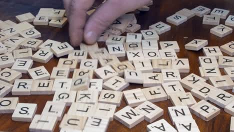 Timelapse:-Right-hand-flips-over-Scrabble-tile-letters-on-wooden-table