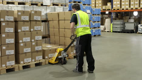 Warehouse-interior-with-stacked-boxes-on-pallets,-yellow-pallet-jack-in-aisle,-fluorescent-lighting