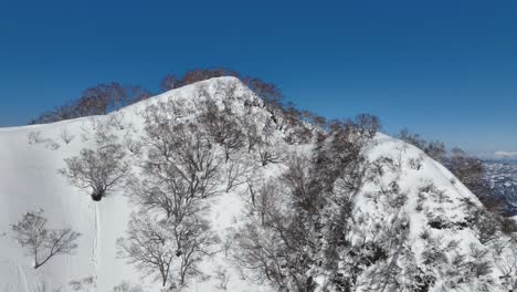 Toma-Aérea-Amplia-En-órbita-Ascendente-Del-Pico-De-La-Cumbre-Del-Monte-Myōkō-De-Japón,-En-Un-Claro-Día-De-Invierno,-Una-Montaña-Volcánica-En-La-Región-Del-Parque-Nacional-Myoko-togakushi-Renzan