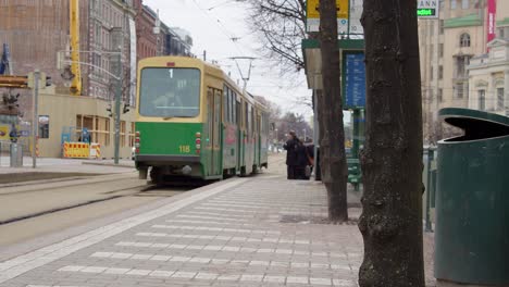 Green-electric-tram-leaves-transit-stop-on-street-in-downtown-Helsinki