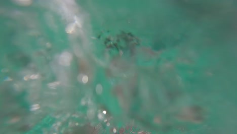 Slow-motion-of-man-in-bathing-suit-on-vacation-holding-camera-as-he-falls-into-swimming-pool-splashing-and-making-bubbles-underwater