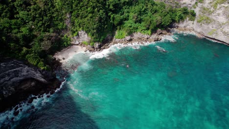 Impresionante-Playa-Rodeada-De-Formaciones-Rocosas-Con-Vegetación-Y-Aguas-Turquesas-En-Nusa-Penida,-Bali,-Indonesia