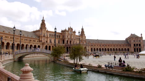 Tourists-Riding-River-Canal-Boats-In-Plaza-de-España-Square-In-Parque-de-María-Luisa,-Seville,-Spain