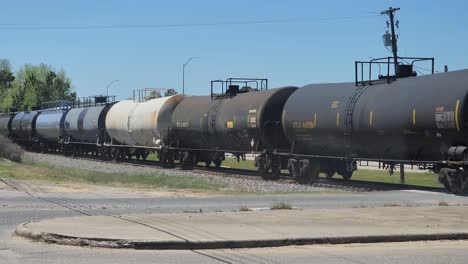 This-is-a-short-video-of-a-train,-moving-through-an-intersection,-with-mostly-tank-rail-cars