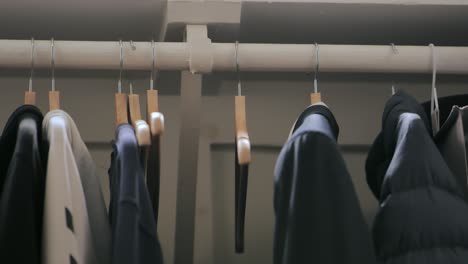 Person-removing-empty-hanger-from-clothing-rack-inside-closet