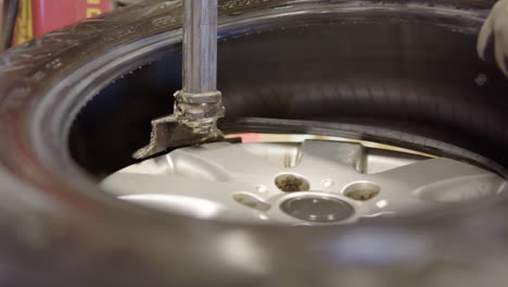 Closeup-of-tyre-technician-removing-rubber-tyre-from-rim-using-machine