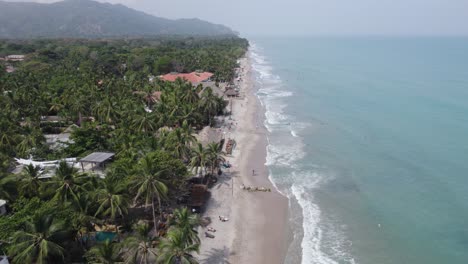 Aerial-dolly-above-tourists-and-families-playing-in-calm-sandy-beaches-of-Palomino-Colombia