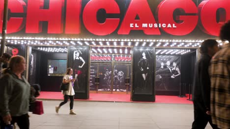 People-walk-past-the-Apolo-Theater,-currently-featuring-the-musical-hit-original-Broadway-production,-Chicago,-in-Spain